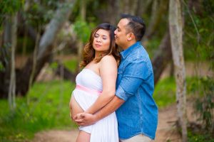 Husband and wife hold each other during maternity photos at Ellwood Butterfly Preserve.