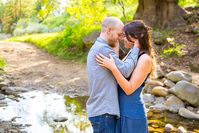 The man and woman embrace by the water.