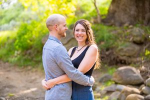The woman laughs while standing in nature.