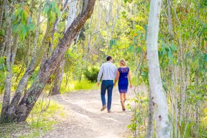 The bride and groom walk together along a rustic path at the Goleta Butterfly Preserve for their engagement photographs.
