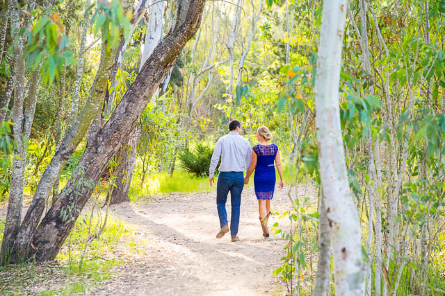The bride and groom walk together along a rustic path at the Goleta Butterfly Preserve for their engagement photographs.