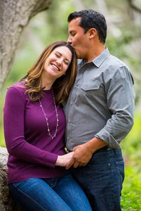 The newly engaged couple kissing while leaning against a tree in Ennisbrook trail in Montecito, CA.