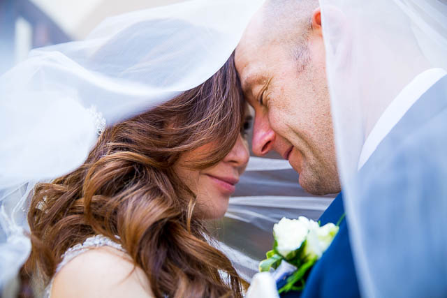 Bride and groom kissing under the veil.