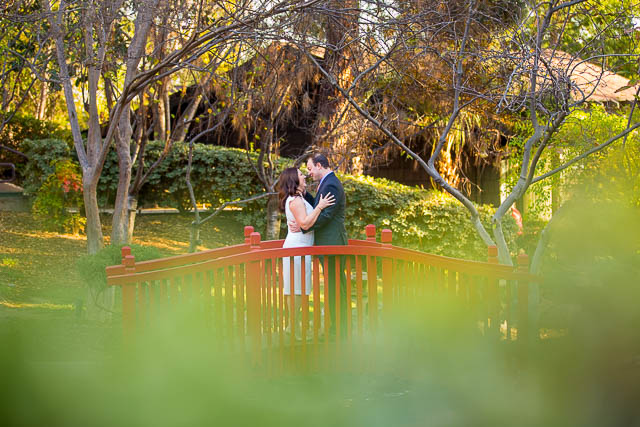 Couple standing together at the red bridge at the Langham Huntington Pasadena Hotel.