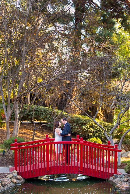 Couple standing together at the red bridge at the Langham Huntington Pasadena Hotel.