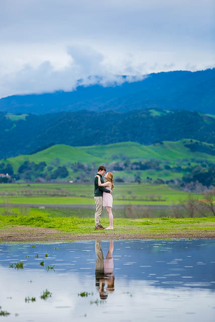Landscape photo of the Solvang mountains and the engaged couple at the Santa Ines Mission.