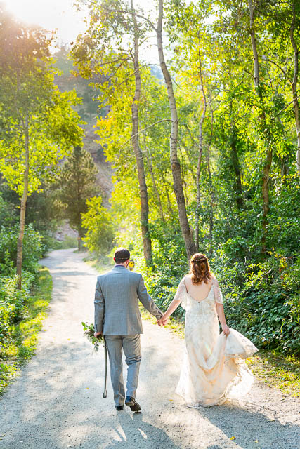 Newlyweds walking on a trail in Boulder, Colorado, while holding hands.
