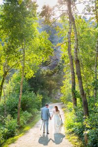 Newlyweds walking on a trail in Boulder, Colorado, while holding hands.