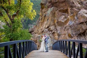 Newlyweds embracing on a bridge on a Boulder, Colorado trail in the Rockies mountains.