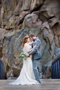 Newlyweds embracing on a bridge on a Boulder, Colorado trail in the Rockies mountains.