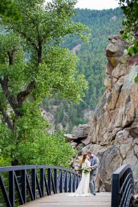 Newlyweds embracing on a bridge on a Boulder, Colorado trail in the Rockies mountains.