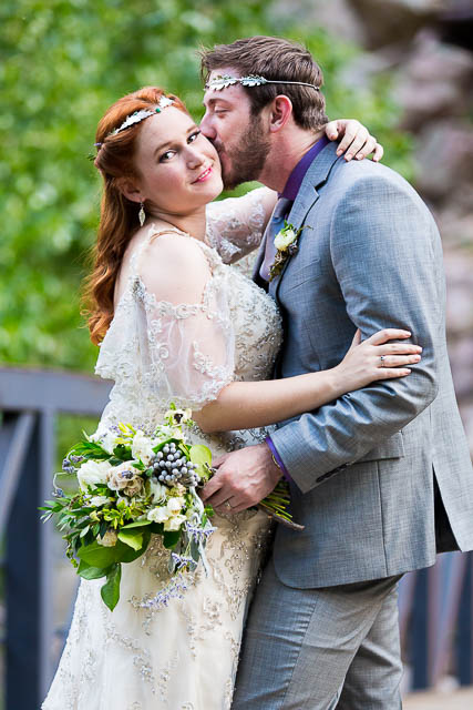 Newlyweds embracing on a bridge on a Boulder, Colorado trail in the Rockies mountains.