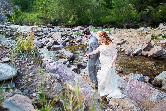 Newlyweds walking on boulders in Boulder, Colorado.