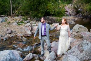 Newlyweds walking on boulders in Boulder, Colorado.
