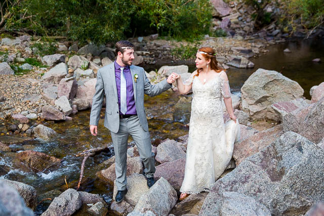 Newlyweds walking on boulders in Boulder, Colorado.