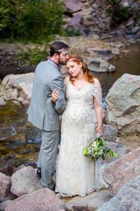 Bride and groom embracing on boulders in Boulder, Colorado.