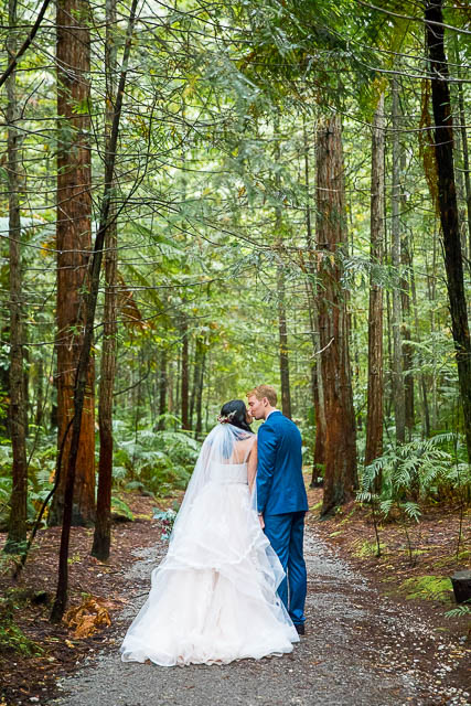 Bride and groom walk together through the Rotorua Redwoods Forest in New Zealand.