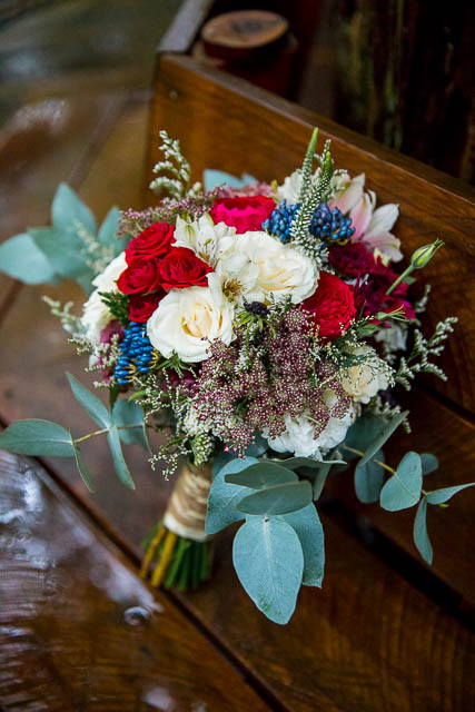 Bridal bouquet with red and white roses, eucalyptus, and other florals in Rotorua wedding.