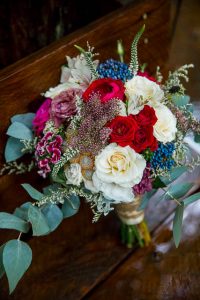 Bridal bouquet with red and white roses, eucalyptus, and other florals in Rotorua wedding.