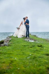 Bride and groom kissing on the Rotorua Lake lake front in New Zealand.