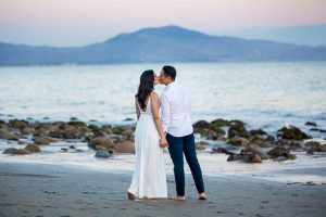 A bride and groom strolling along the beach in Santa Barbara during their engagement photo session.