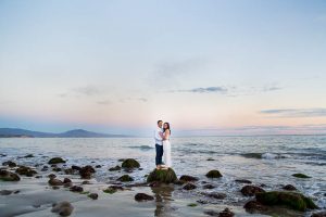 A bride and groom strolling along the beach in Santa Barbara during their engagement photo session.