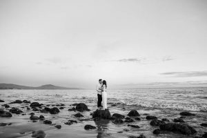 A bride and groom strolling along the beach in Santa Barbara during their engagement photo session.