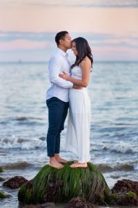 A couple snuggling together on the beach in Santa Barbara at Sunset during their engagement photo session.