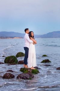 A couple snuggling together on the beach in Santa Barbara at Sunset during their engagement photo session.