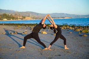 The engaged couple doing yoga poses during their yogi engagement photoshoot.
