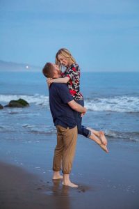 Couple having fun, being playful at their Santa Barbara beach engagement photoshoot.