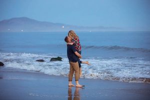 Couple having fun, being playful at their Santa Barbara beach engagement photoshoot.