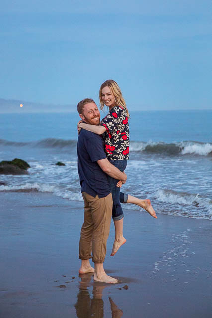 Couple having fun, being playful at their Santa Barbara beach engagement photoshoot.