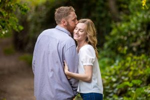Couple embracing by the flowers during their Santa Barbara engagement photoshoot.