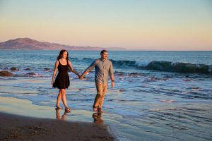 Fiancé and Fiancée strolling together during their romantic Santa Barbara beach engagement photoshoot.