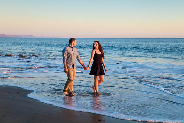 Fiancé and Fiancée strolling together during their romantic Santa Barbara beach engagement photoshoot.