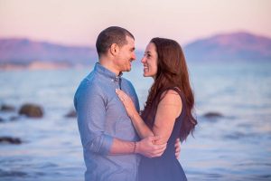 Engaged couple at the beach with a cotton candy sky sunset.
