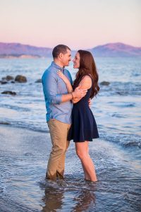 Engaged couple at the beach with a cotton candy sky sunset.