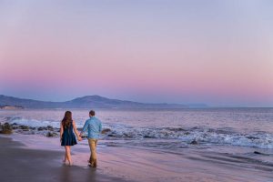 Fiancé and Fiancée strolling together during their romantic Santa Barbara beach sunset engagement photoshoot.