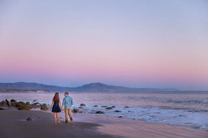 Fiancé and Fiancée strolling together during their romantic Santa Barbara beach sunset engagement photoshoot.