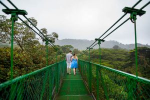 Engaged couple walking across the Selvatura Park Monteverde cloud forest in Costa Rica during their adventurous engagement session.