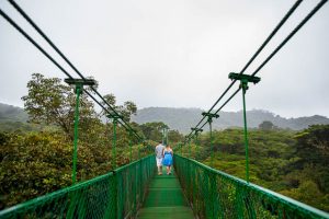 Engaged couple walking across the Selvatura Park Monteverde cloud forest in Costa Rica during their adventurous engagement session.