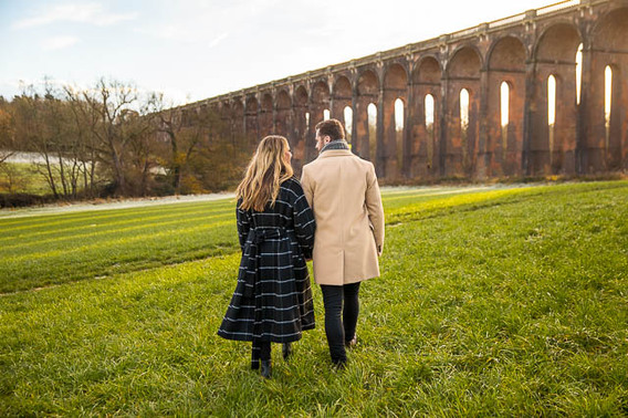 Engaged couple walking together at the Sussex Ouse Valley Viaduct.