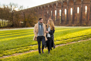 Engaged couple walking together at the Sussex Ouse Valley Viaduct.