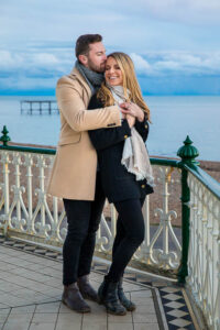 Newly engaged couple hugging at Brighton Beach in England.