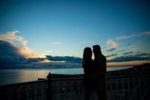 Silhouette of newly engaged couple hugging at Brighton Beach in England.